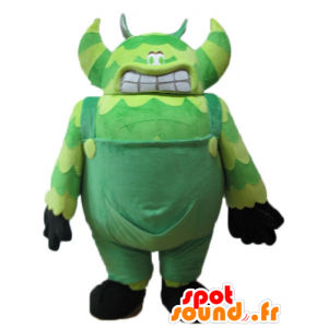 Grön monster maskot, i overall, mycket stor och rolig -