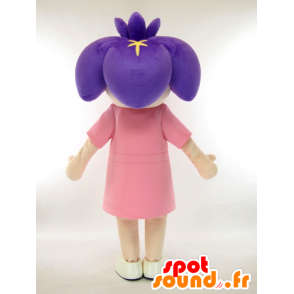 Liten flickamaskot med en purpurfärgad blomma på hennes huvud -